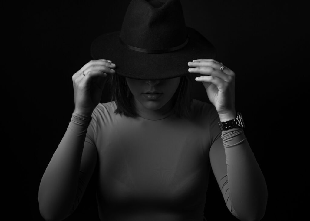 Artistic black and white portrait of a woman in a fashionable black hat.